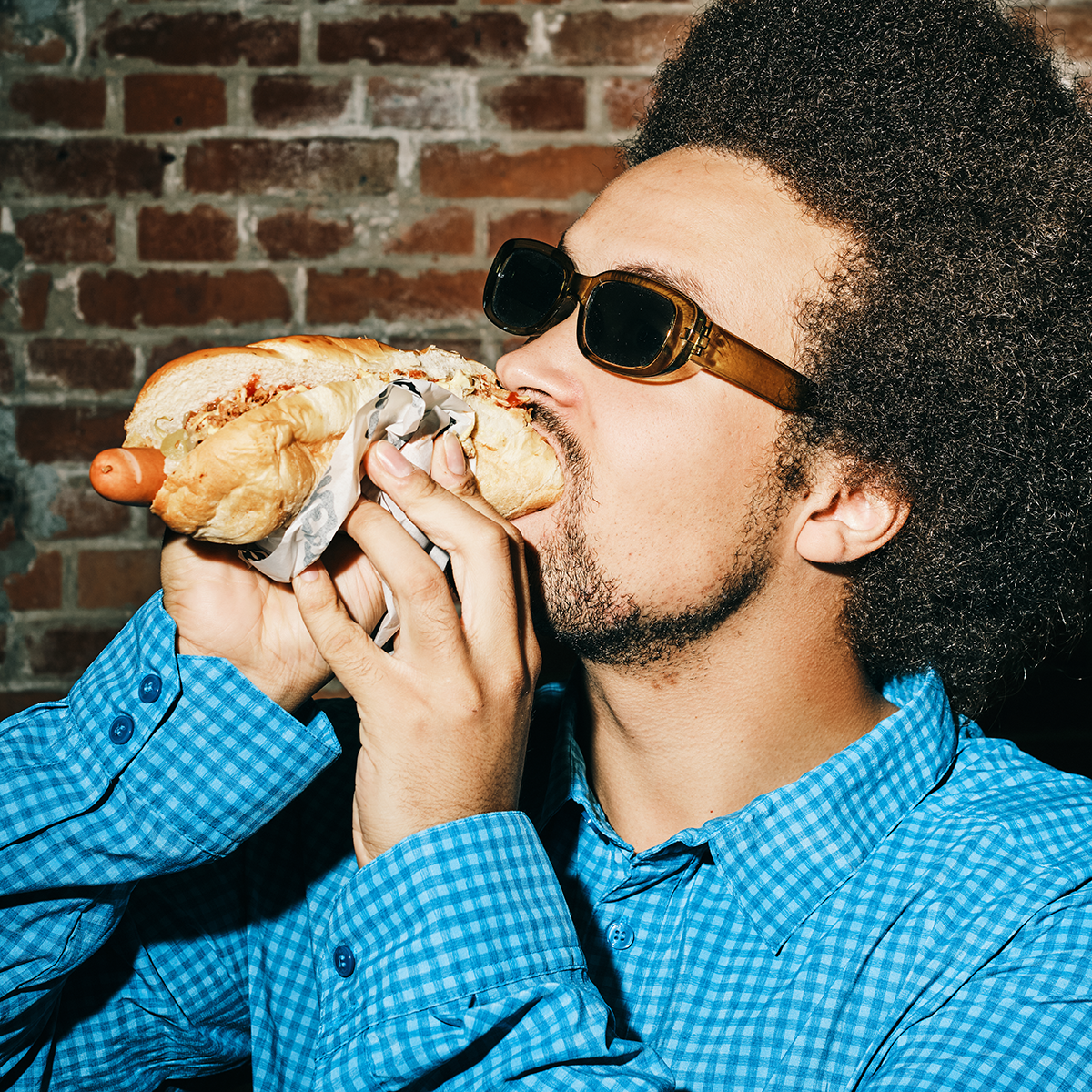 Dark hair guy eating hot dog